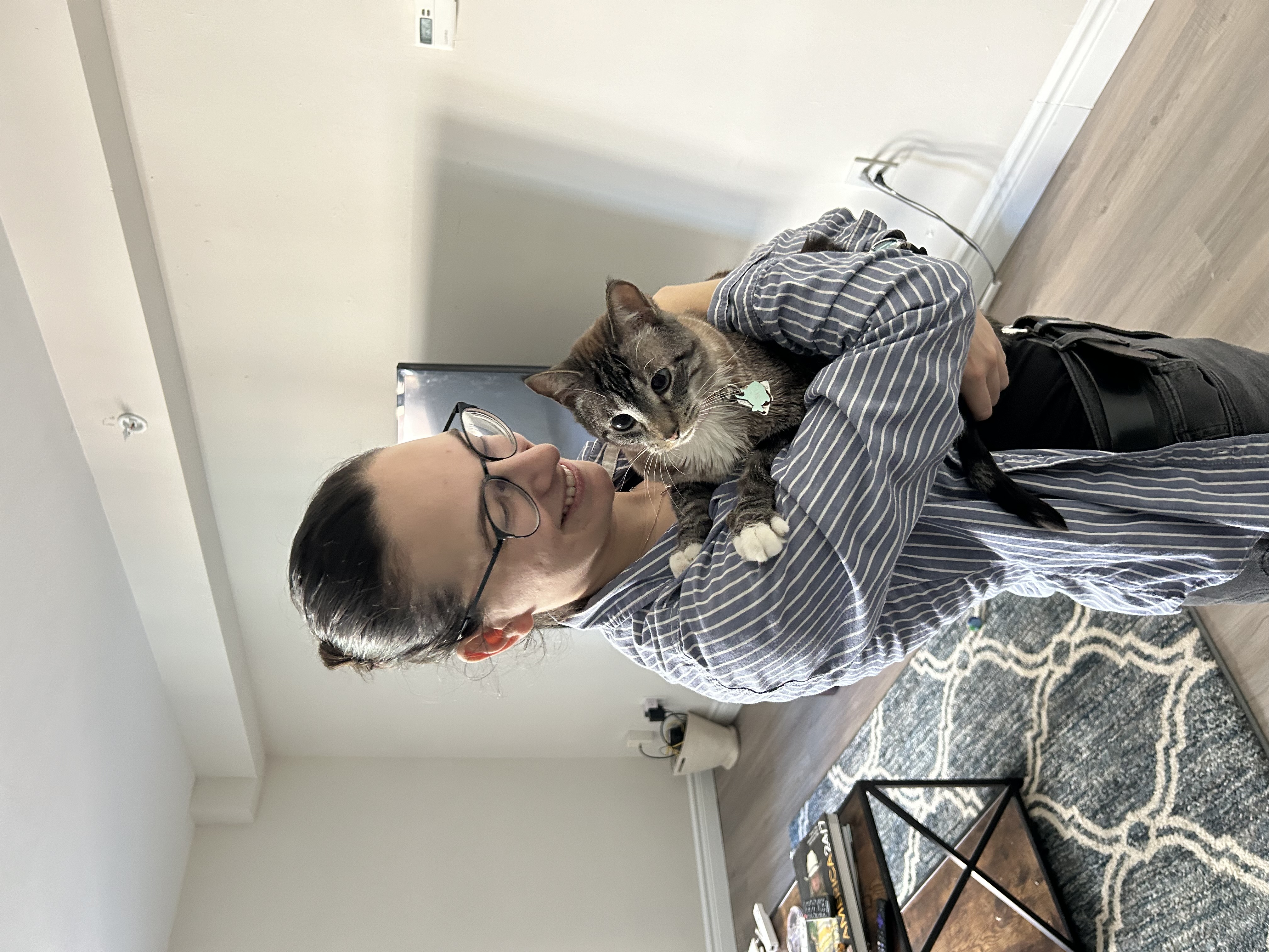 Kelsey cuddling a tabby cat in a home
