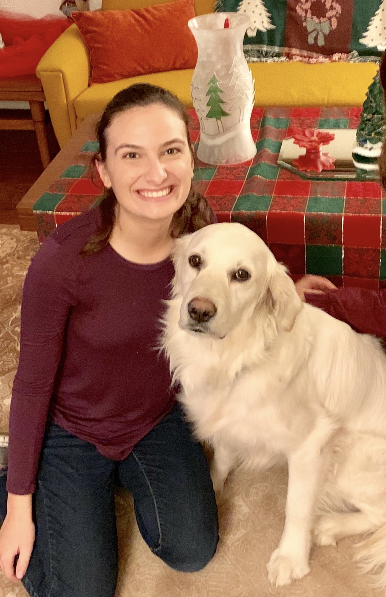 Kelsey smiling with a golden retriever indoors